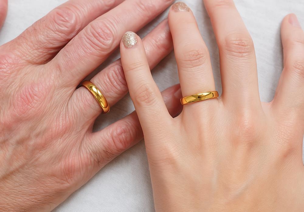 A slender hand wearing a diamond wedding Ring on their ring finger