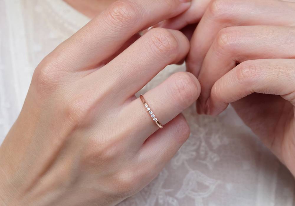 A slender hand wearing a Diamond Ring on their ring finger
