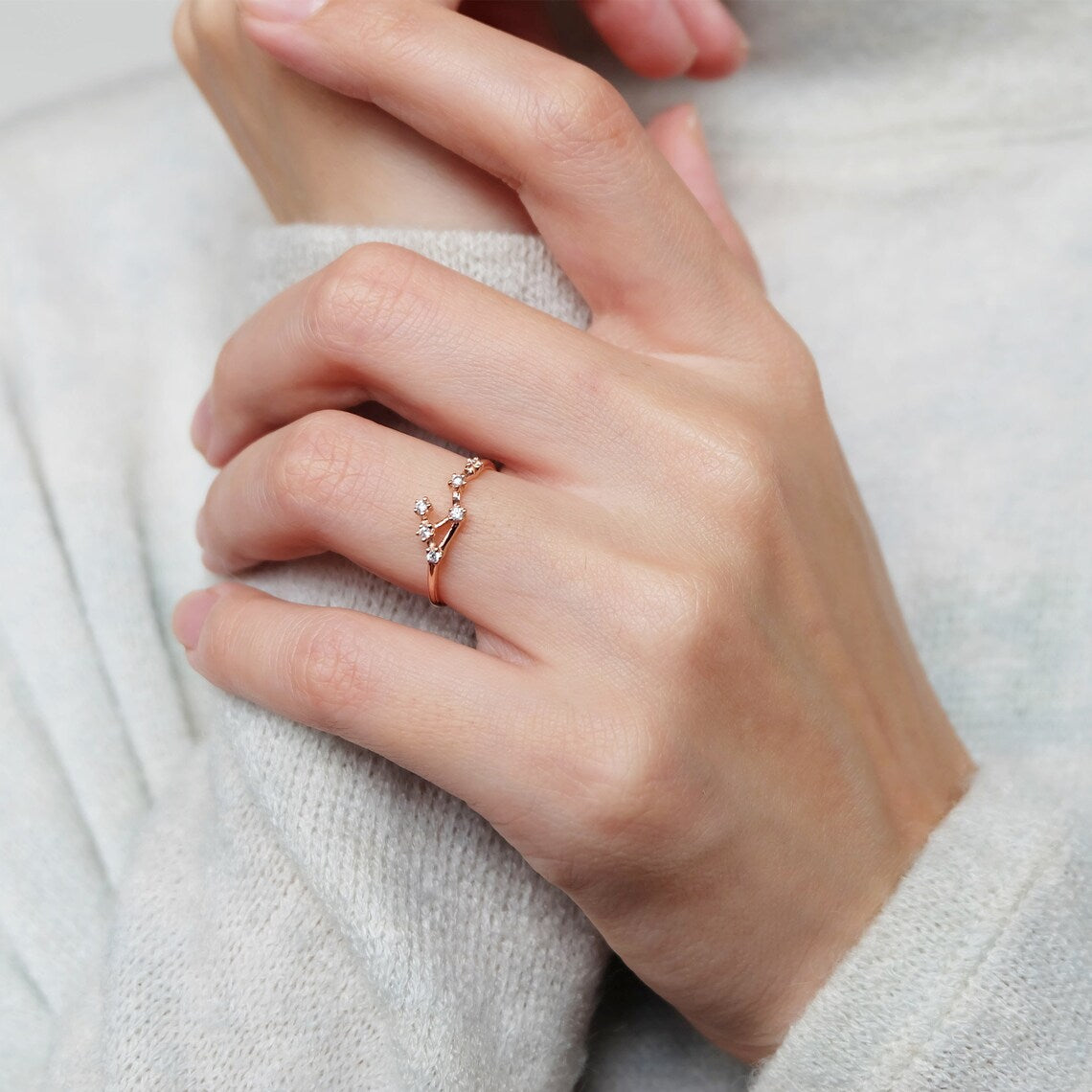 A person wearing an 18K rose gold Libra Zodiac Diamond ring
