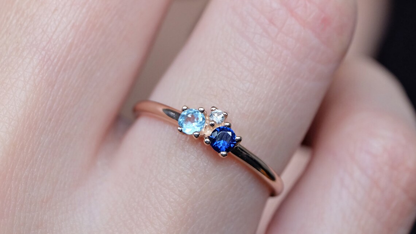 A hand wearing an aquamarine sapphire ring